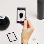 hand holding card with black coffin crystal surrounded by tarot reading supplies