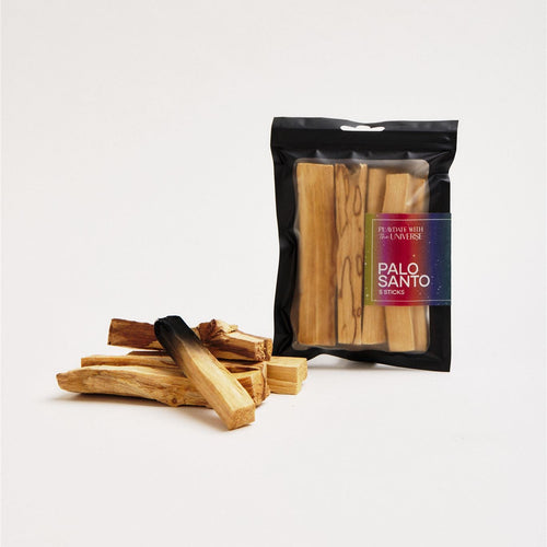sticks of palo santo stacked next to the packaging containing more palo santo