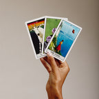 Hand holding 3 tarot cards, the fool, the devil and the  of pentacles or diamonds