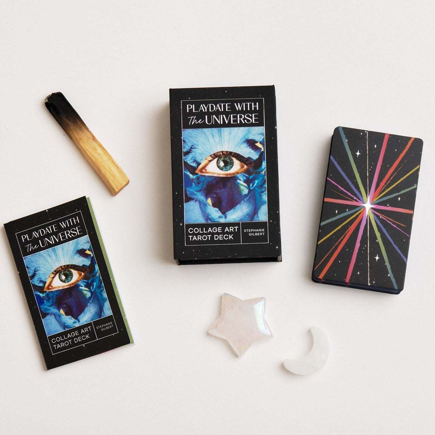 Tarot deck, moon and star crystals, palo santo arranged on a white background