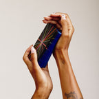 two hands holding a stack of tarot cards with a blue edge detail 