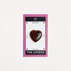 mahogany obsidian heart shaped crystal on white surface
