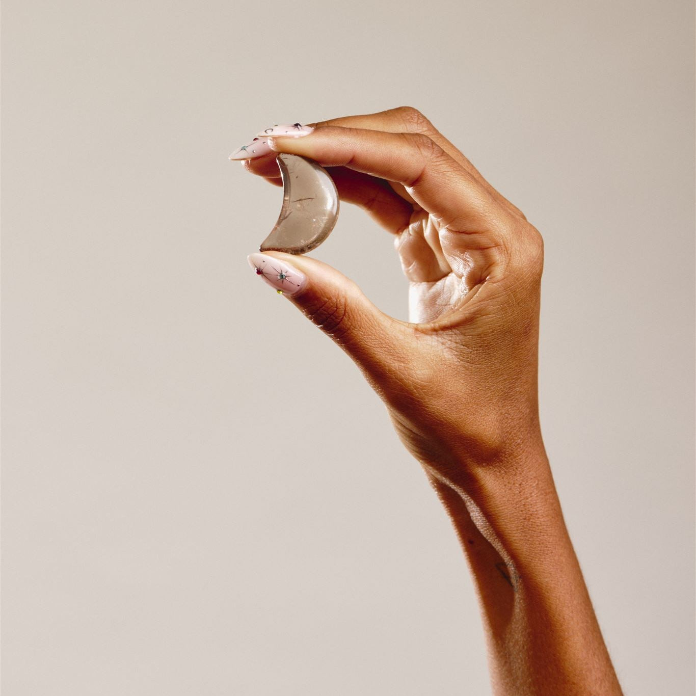 hand holding smokey quartz moon shaped crystal