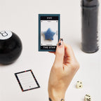 hand holding star crystal on a card surrounded by tarot reading supplies